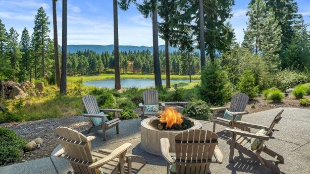 A patio with Adirondack chairs, a fire pit, and a view of a lake surrounded by trees. - Golf View, Hot Tub, Suncadia Pool Access (Cle Elum)