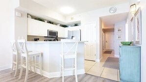 Una cocina moderna con armarios blancos, una isla central con taburetes altos y un mueble color turquesa.