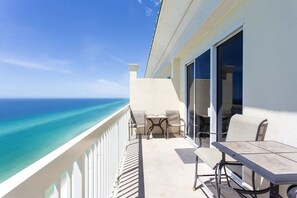 Un balcon avec vue sur l’océan, une table et des chaises, et une porte-fenêtre coulissante.