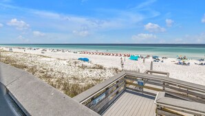 Ein Strand mit einer hölzernen Promenade, die zum Ufer führt, bewölkter Himmel und ruhiges Meer.