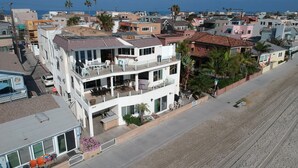 A multi-story residential building with balconies, a street view, and a beach in the background. - The BEST of the best on Mission Bay! (San Diego)