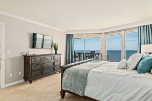 Relax in this serene ocean-view room featuring a large bed, flat-screen TV, and a cozy reading nook.