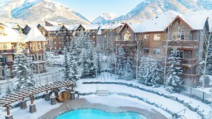 Un resort con piscina, árboles cubiertos de nieve y vistas a la montaña.