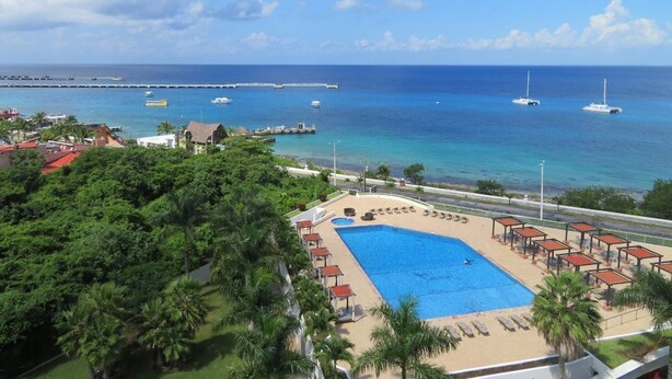 A resort with a swimming pool, beach chairs, and a view of the ocean and boats. - Luxurious 4 Bed/4 Bath with Million Dollar Views (Cozumel Island)
