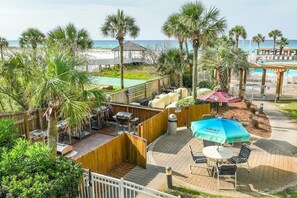 Enjoy a beachfront patio with a wooden deck, barbecue equipment, and a seating area with a table and chairs.