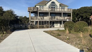 A multi-story building with a balcony on the second floor, a sign reading "SmileAway," and a basketball hoop in the foreground. - A Beach Vacation destination. EV friendly. (Corolla)
