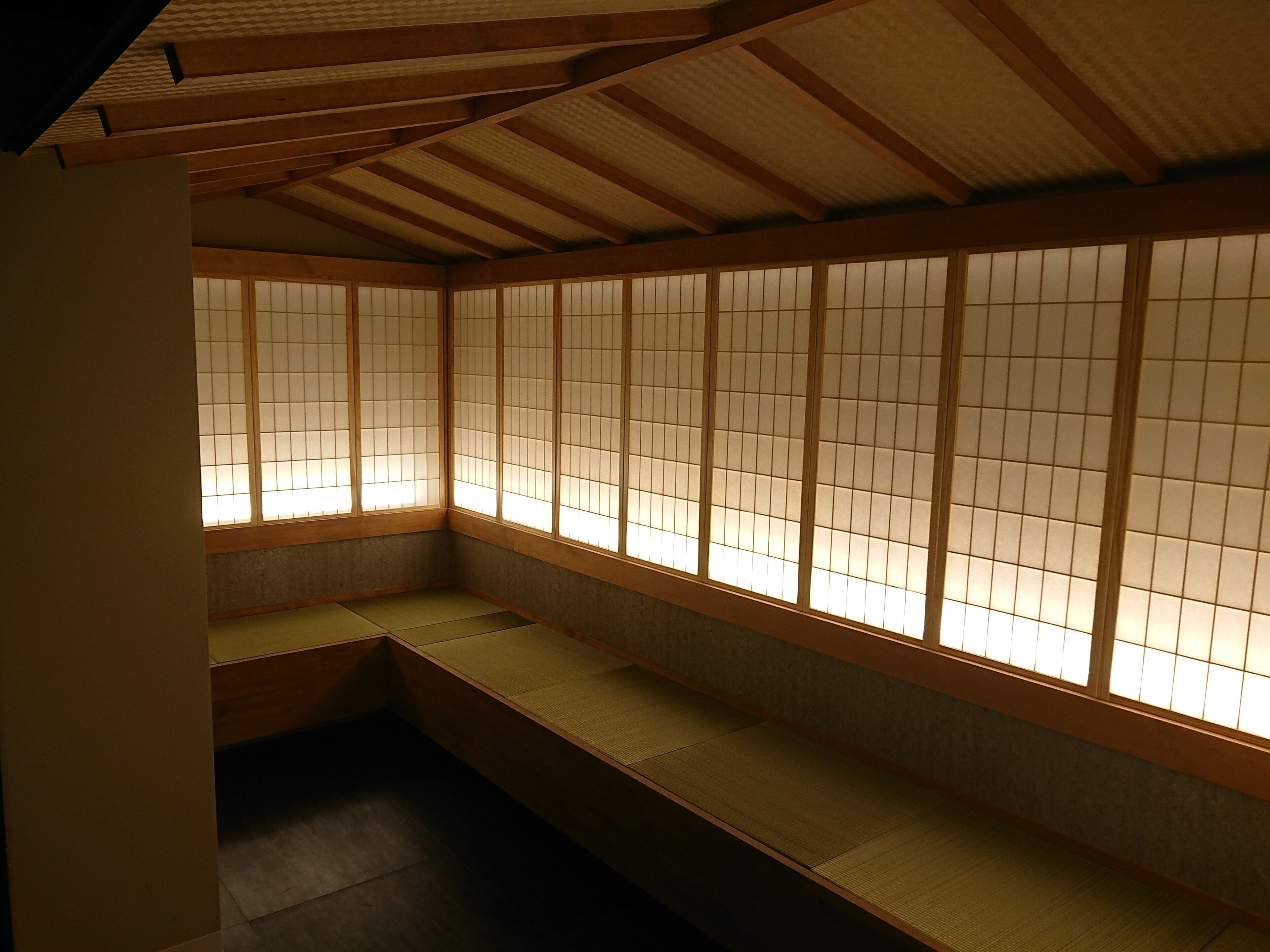 Une pièce de style japonais traditionnel, avec un sol recouvert de tatamis, des paravents coulissants en papier de riz (shoji) et un plafond bas.