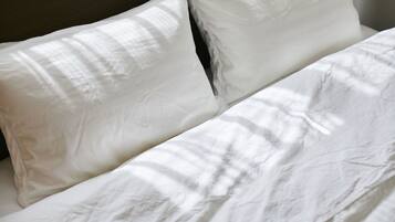 A bed with white linens and pillows.