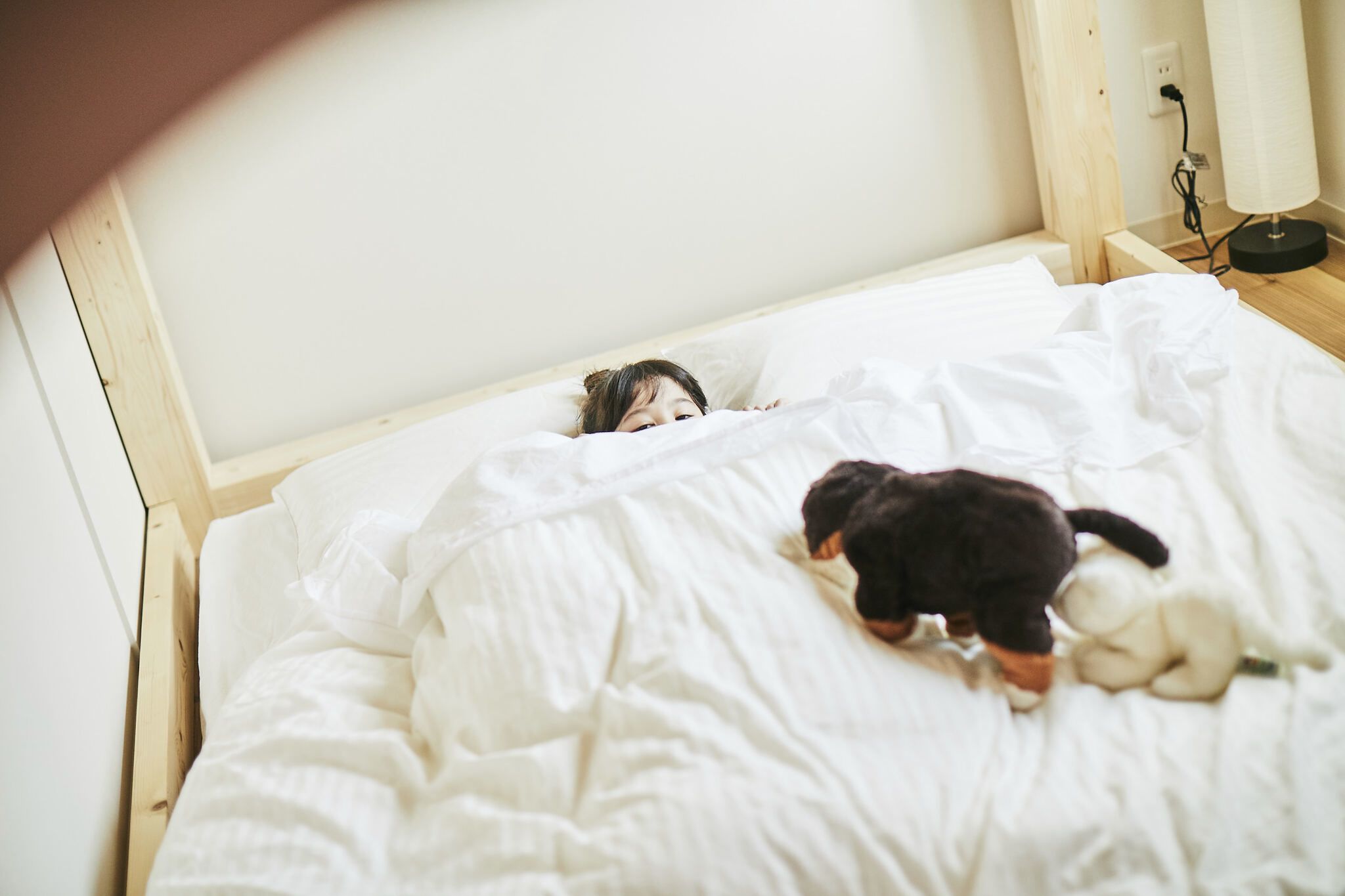 Un letto con testiera in legno, coperta bianca e un peluche.