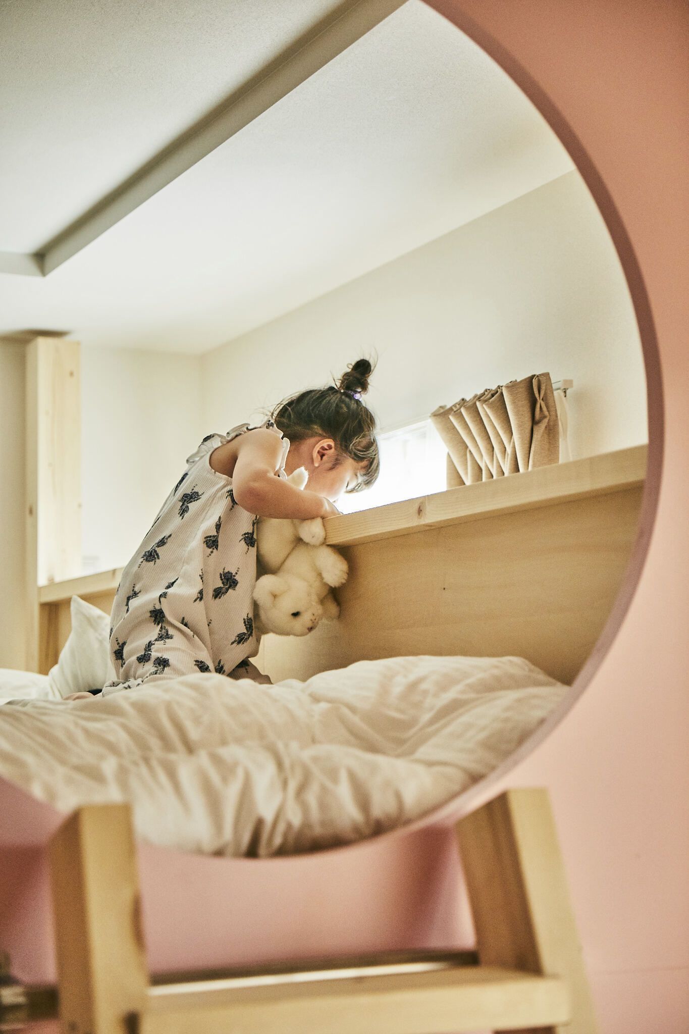 Un lit superposé avec une personne qui dort, une fenêtre et un rideau.