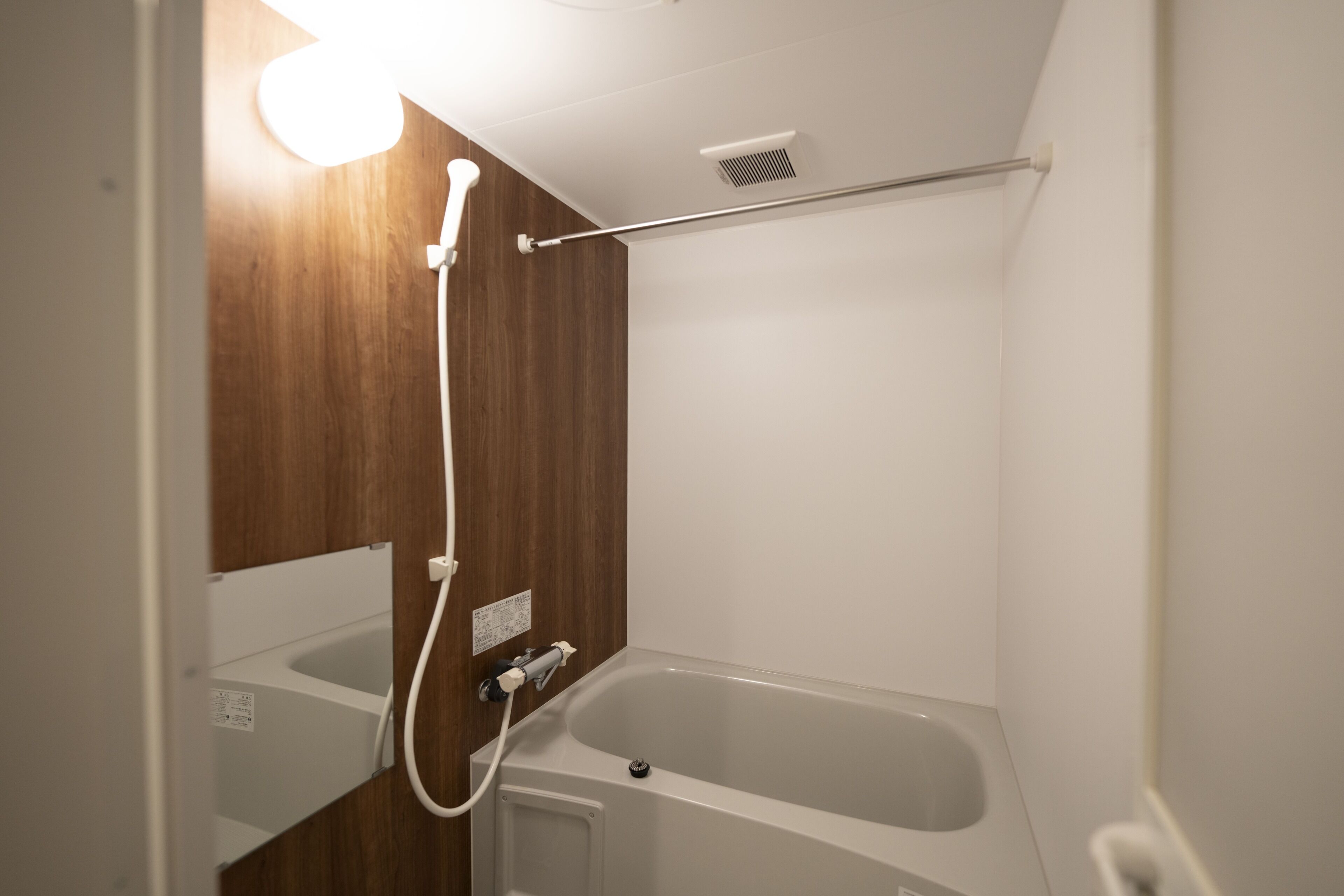 A bathroom with a bathtub, a shower, and a wooden wall.