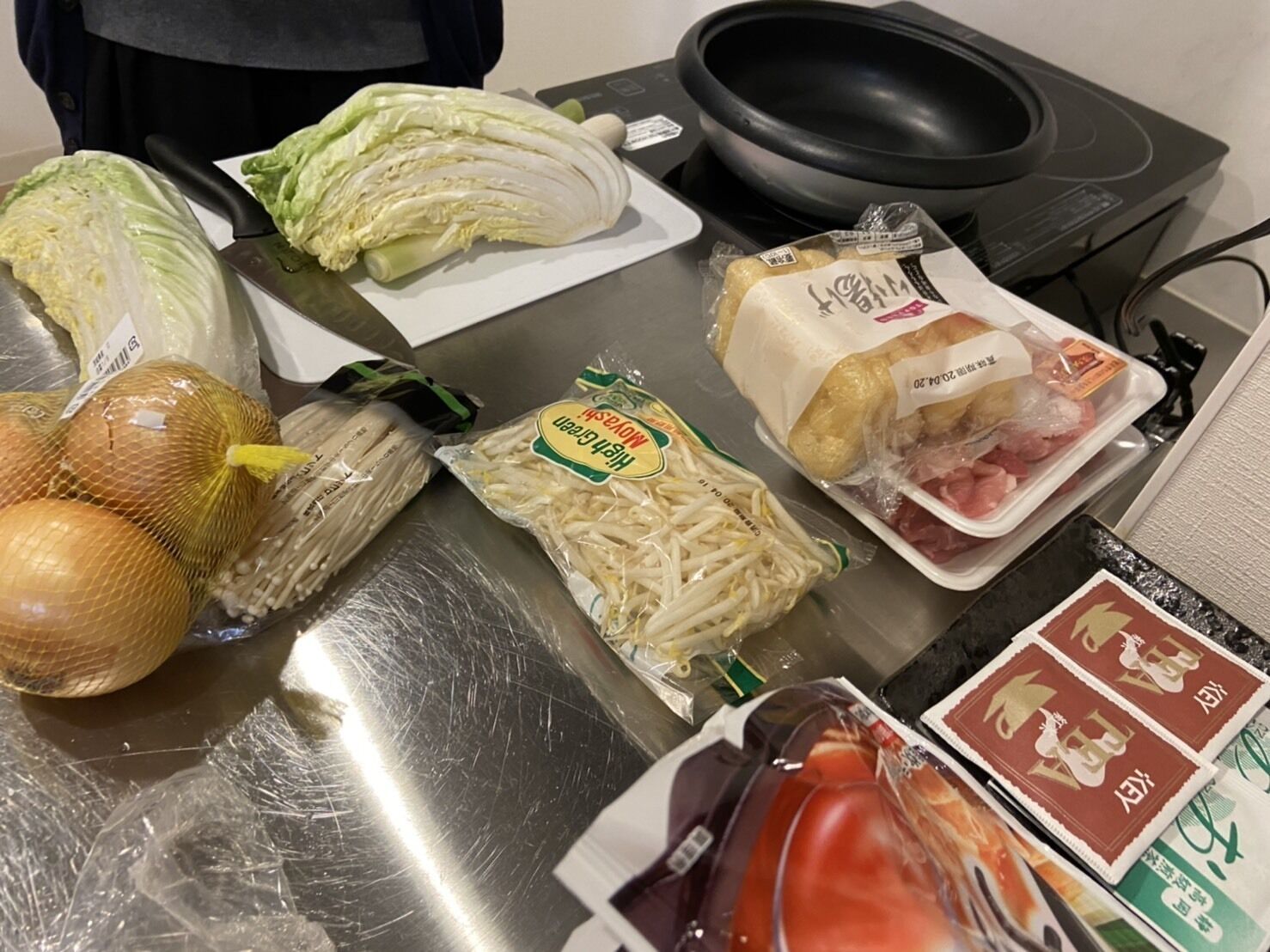 A kitchen counter with various food items including cabbage, onions, mushrooms, and packaged meat.