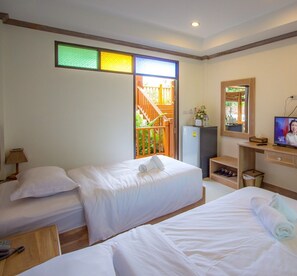 Habitación de hotel con dos camas, un escritorio, un televisor y una pequeña kitchenette.