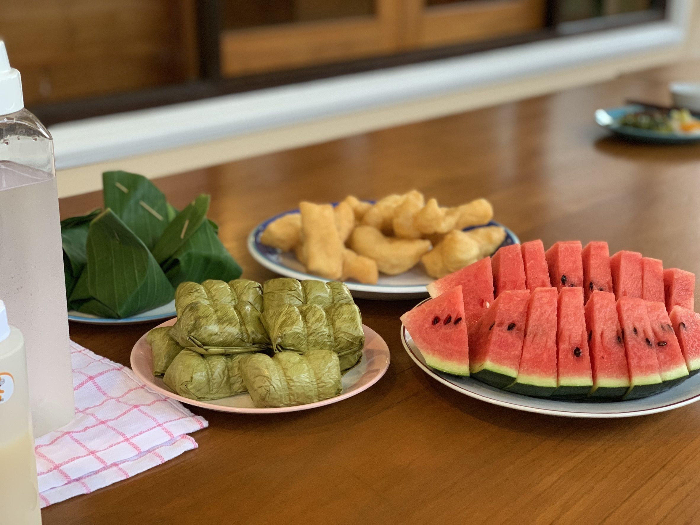 A table with plates of stuffed grape leaves, fried dough, and watermelon slices.