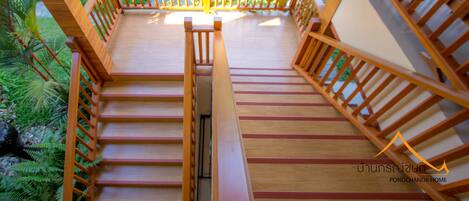 A wooden staircase leading to a deck with a view of a tropical garden.