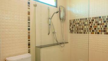 A bathroom with a toilet, a shower with a glass door, and a tiled wall with a mosaic pattern.
