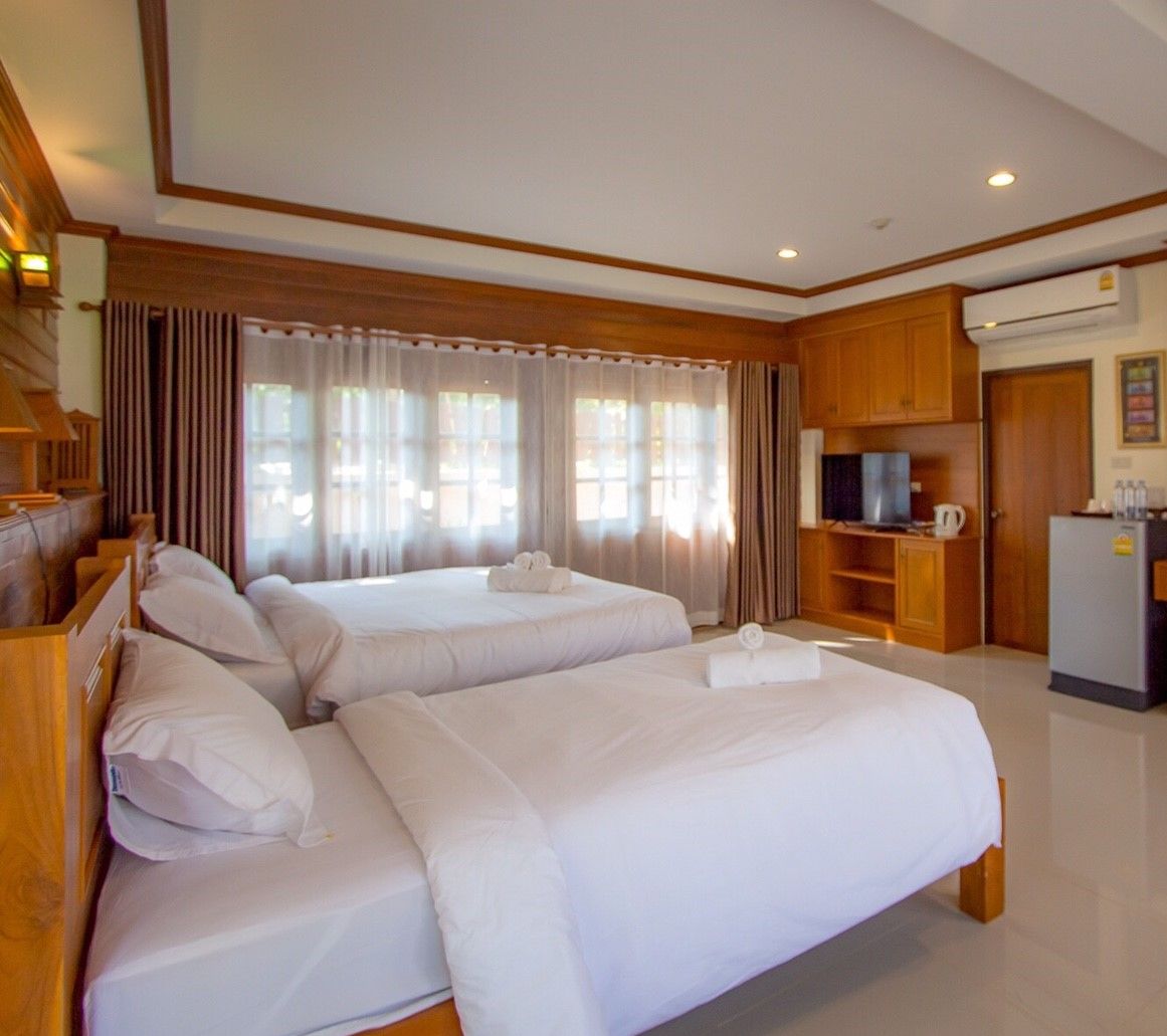 A hotel room with two beds, a television, a refrigerator, and a kitchenette.