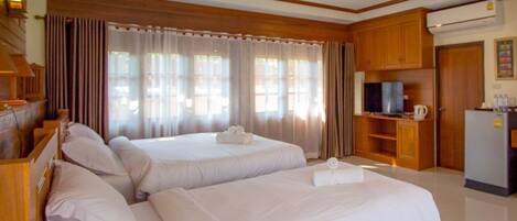 A hotel room with two beds, a television, a refrigerator, and a kitchenette.