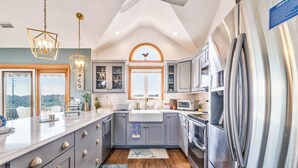 A modern kitchen with grey cabinets, stainless steel appliances, and a large island.