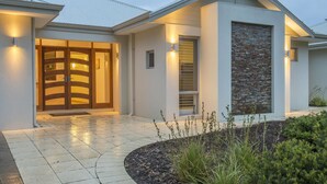 A modern house with a large front door, a stone accent wall, and a well-lit entrance. - Juniper Metricup House - luxury rural retreat (Wilyabrup)