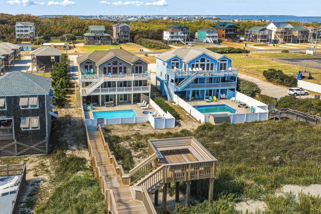 Una zona residencial costera con varias casas, una terraza de madera y una piscina.