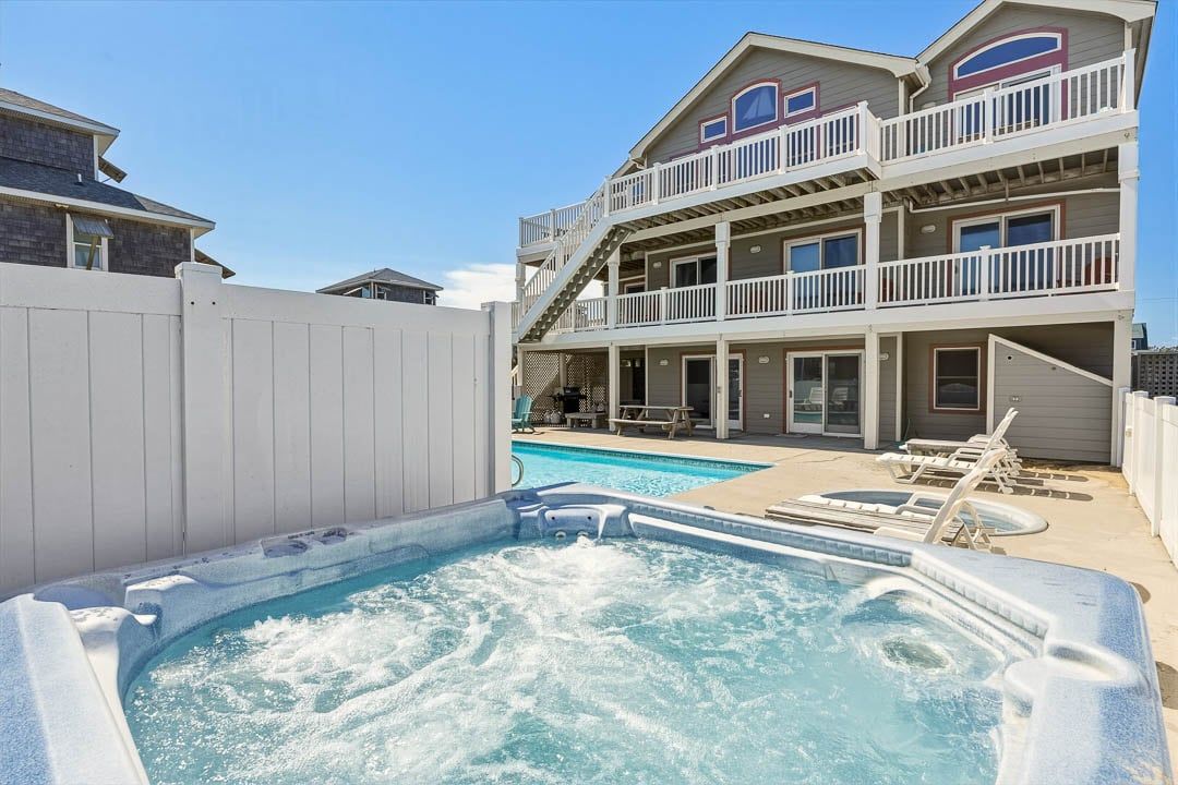 Un bâtiment à deux étages avec une piscine et un jacuzzi situés au premier plan.