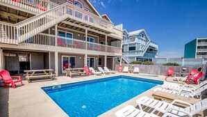 A pool area with lounge chairs and a wooden deck. - The Lodge | Oceanfront | Private Pool, Hot Tub | Nags Head (Nags Head)
