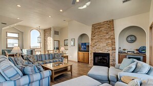 A spacious living room with a sectional sofa, a fireplace, and a stone accent wall. - The Lodge | Oceanfront | Private Pool, Hot Tub | Nags Head (Nags Head)