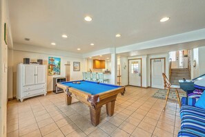 A pool table in a room with tiled flooring, a white cabinet, and a blue sofa. - The Lodge | Oceanfront | Private Pool, Hot Tub | Nags Head (Nags Head)