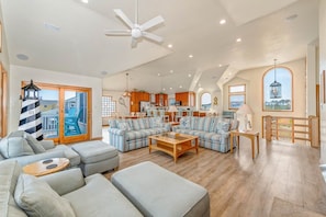 A spacious living area with a large sofa set, a coffee table, and a ceiling fan. - The Lodge | Oceanfront | Private Pool, Hot Tub | Nags Head (Nags Head)