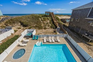 A swimming pool with lounge chairs, a hot tub, and a deck leading to the beach. - The Lodge | Oceanfront | Private Pool, Hot Tub | Nags Head (Nags Head)