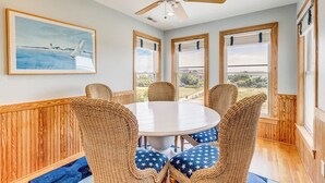 Un coin repas avec une table ronde, des chaises en osier et un ventilateur de plafond.