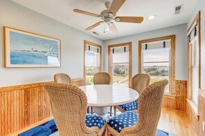 A dining area with a round table, wicker chairs, and a ceiling fan. - Corolla Crush | 485 ft from the beach | Private Pool, Hot Tub | Corolla (Corolla)