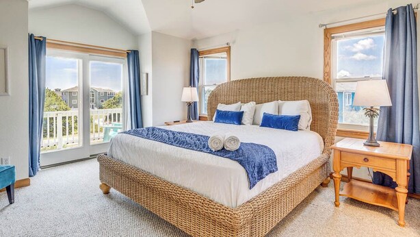 Une chambre spacieuse avec un grand lit, un ventilateur de plafond et une vue sur l’extérieur.