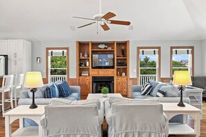 A living room with a fireplace, two sofas, a television, and a ceiling fan. - Corolla Crush | 485 ft from the beach | Private Pool, Hot Tub | Corolla (Corolla)