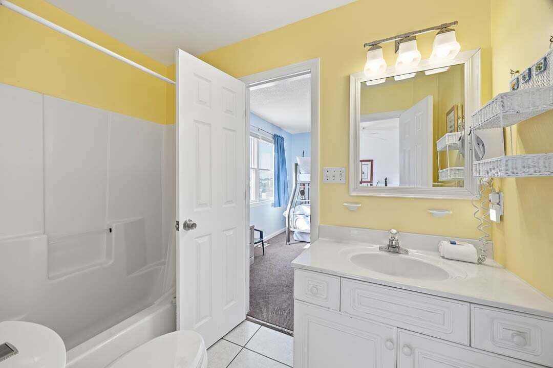 A bathroom with a white bathtub, a sink with a mirror, and a shower area.