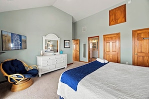 A bedroom with a bed, a dresser, a chair, and two doors.