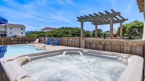 A hot tub with a wooden pergola, a pool, and lounge chairs. - Legacy | 980 ft from the beach | Dog Friendly, Private Pool, Hot Tub | Corolla (Corolla)