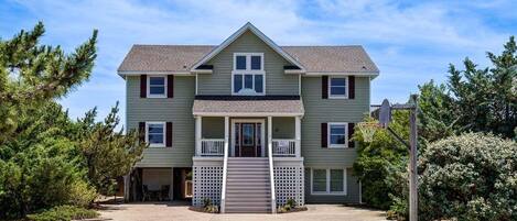 A two-story residential building with a front porch, a garage, and a basketball hoop.