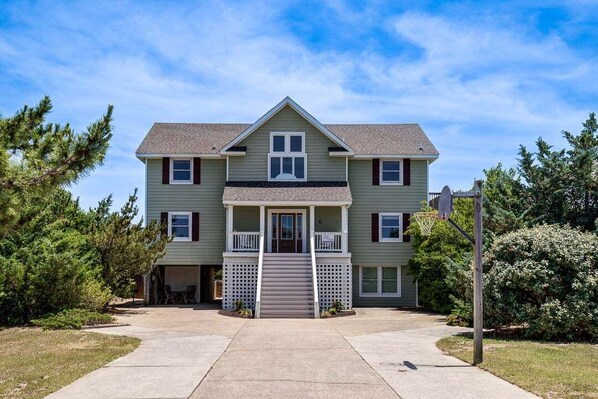 A two-story residential building with a front porch, a garage, and a basketball hoop.