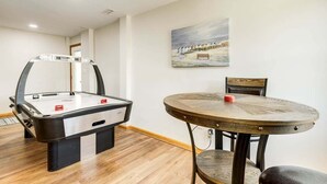 A room with a foosball table, a round wooden table, and a painting on the wall. - Legacy | 980 ft from the beach | Dog Friendly, Private Pool, Hot Tub | Corolla (Corolla)