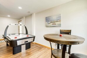 A room with a foosball table, a round wooden table, and a painting on the wall.
