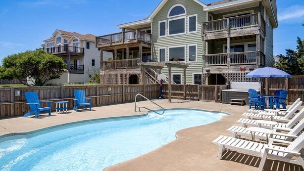 A pool area with a wooden deck, lounge chairs, and a barbecue setup. - Legacy | 980 ft from the beach | Dog Friendly, Private Pool, Hot Tub | Corolla (Corolla)