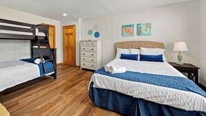 A bedroom with a bunk bed, a single bed, a dresser, and two wall art pieces. - Legacy | 980 ft from the beach | Dog Friendly, Private Pool, Hot Tub | Corolla (Corolla)