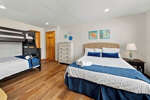 Una camera da letto con una cuccetta, un letto singolo, un comò e due quadri appesi al muro.