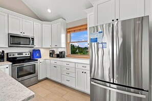 Una cucina moderna con mobili bianchi, elettrodomestici in acciaio inossidabile e una finestra con vista.
