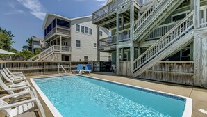 Une piscine avec des chaises longues et une terrasse en bois.