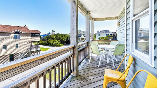 Une terrasse en bois, agréée de mobilier d’extérieur, qui offre une vue sur un quartier résidentiel.