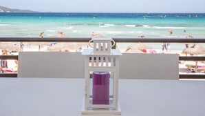 Vista de la playa desde un balcón, con una mesa y un farol morado al frente.