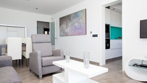 Una sala de estar moderna con un sofá gris, una mesa de centro blanca y un cuadro en la pared.